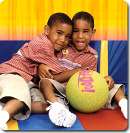 twins sitting on the floor with a ball, one hugging the other