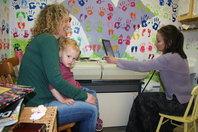 blonde Mom smiling, holding babe on her lap with Dr. Herrmann