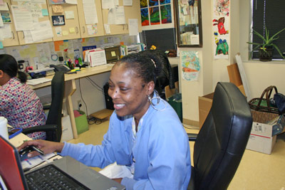 Kisha working on the computer in the office and smiling