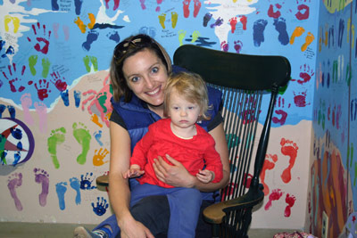 smiling Mom holding daughter in rocking chair in the waiting room