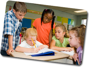 five students at a desk in a classroom working together